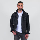 Man wearing a black denim jacket over a white shirt on a plain background
