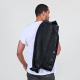 Man wearing a black jacket over his shoulder against a white background