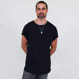 Man wearing a black t-shirt and gray jeans standing against a white background