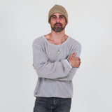 Man wearing a gray long sleeve tee and dark jeans standing against a white background