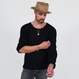 Man wearing a black long sleeve tee and gray jeans standing against a white background