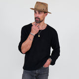 Man wearing a black long sleeve tee and gray jeans standing against a white background