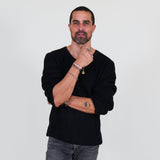 Man wearing a black long sleeve tee and gray jeans standing against a white background