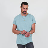 Man wearing a teal t-shirt and dark jeans standing against a white background