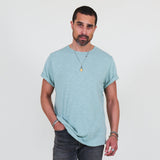 Man wearing a teal t-shirt and dark jeans on a white background
