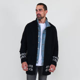 Man wearing a black cardigan with white patterns, white shirt and gray jeans on a white background