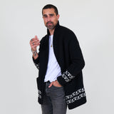 Man wearing a black cardigan with white patterns, white shirt and gray jeans on a white background