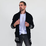 Man wearing a black cardigan with white patterns, white shirt and gray jeans on a white background