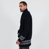 Man wearing a black cardigan with white patterns, white shirt and gray jeans on a white background