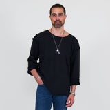 Man wearing a black sweater and blue jeans standing against a white background