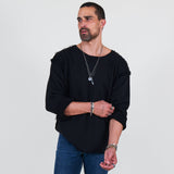 Man wearing a black sweater and blue jeans standing against a white background