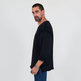 Man wearing a black sweater and blue jeans standing against a white background