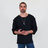 Man wearing a black sweater and blue jeans standing against a white background