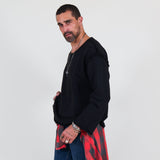 Man wearing a black sweater and blue jeans standing against a white background