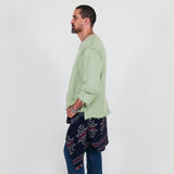 Person wearing a light green shirt and blue pants on a white background